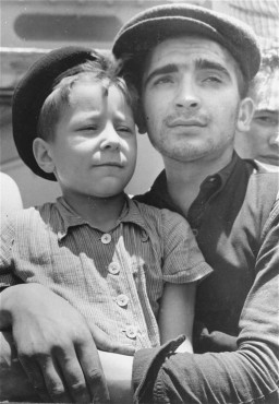 Eight-year-old Yisrael Meir (Lulek) Lau is held by a fellow  Buchenwald survivor, Elazar Schiff, as they arrive in Palestine aboard ... [LCID: 69435]