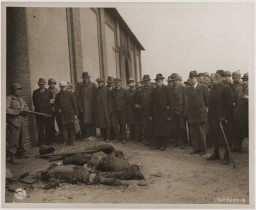 An American soldier stands guard as mayors and citizens of local towns view the corpses of inmates of the Rottleberode subcamp, who ... [LCID: 76687]