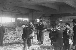 Sous les ordres de la Première armée américaine, des civils allemands se préparent à utiliser un brancard pour évacuer les cadavres de victimes du camp de concentration de Dora-Mittelbau, près de Nordhausen. Allemagne, après le 10 avril 1945.