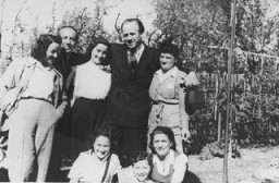 Oskar Schindler standing (second from right) with some of the people he rescued. [LCID: 03411]