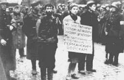 Soldats allemands exhibant trois jeunes gens dans les rues de Minsk avant leur exécution. L'affiche dit : "Nous sommes des partisans qui avons tiré sur des soldats allemands." Minsk, Union soviétique, le 26 octobre 1941.