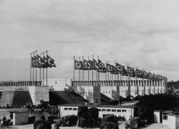 Nazi flags wave above the stadium for the Nazi Party rally grounds in Nuremberg. Architects like Albert Speer constructed monumental edifices in a sterile classical form meant to convey the “enduring grandeur” of the National Socialist movement. Photograph taken in Nuremberg, Germany, between 1934 and 1936. 