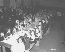 Fête de Hanoukka pour des enfants juifs au camp de personnes déplacées de Fürth. Les cadeaux étaient offerts par les familles des Américains résidant au poste militaire de Nuremberg. Allemagne, 9 décembre 1947.