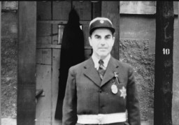 Yahudi bir polis memurunun Uluslararası Kızıl Haç’ın Theresienstadt gettosunu ziyareti sırasında çekilen fotoğrafı. SS, heyeti, gettonun kendi kendini yöneten bir Yahudi yerleşimi olduğuna inandırma suretiyle kandırmıştır. Çekoslovakya, 23 Haziran 1944.