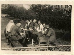 Karl Höcker (on left, looking at the camera) relaxes with SS physicians, including Dr. Fritz Klein (far left), Dr. Horst Schumann (partially obscured next to Klein, identified from other photographs), and Dr. Eduard Wirths (third from right, wearing tie).
From Karl Höcker's photograph album, which includes both documentation of official visits and ceremonies at Auschwitz as well as more personal photographs depicting the many social activities that he and other members of the Auschwitz camp staff enjoyed. These rare images show Nazis singing, hunting, and even trimming a Christmas tree. They provide a chilling contrast to the photographs of thousands of Hungarian Jews deported to Auschwitz at the same time. 
 