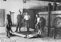 Survivors of the Dachau concentration camp demonstrate the operation of the crematorium by preparing a corpse to be placed into one of the ovens. Dachau, Germany, April 29–May 10, 1945.
This image is among the commonly reproduced and distributed, and often extremely graphic, images of liberation. These photographs provided powerful documentation of the crimes of the Nazi era.