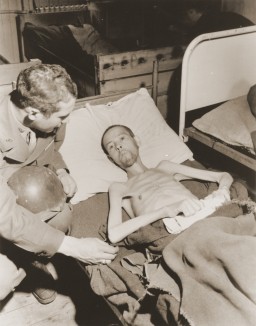 Soon after liberation, a US soldier examines an emaciated forced laborer, a Soviet prisoner of war. [LCID: 80927]