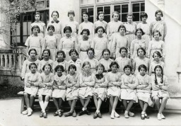 A group of Tunisian schoolgirls wearing aprons. Nadia Cohen is in the first row, third from the left. Tunis, Tunisia, ca. 1930-1935.
Nadia Cohen was born on January 17, 1924, in Tunis. Nadia's parents came from Orthodox households, but her father left the yeshiva at the age of seven to study Italian, Arabic, and accounting in a French school. In 1938, Nadia was sent to a boarding school in France. She returned home for a visit in the summer of 1939 but could not return to school that fall due to the outbreak of the war.
Immediately after the Allied landings in Algeria and Morocco, the Germans occupied Tunisia. After the occupation, an SS officer came to the Cohen's house and confiscated everything leaving only the table and chairs for the Germans to use. They gave the family 24 hours to pack and leave and then expropriated the home to use as a barracks for soldiers.