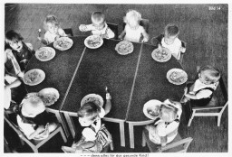 In this Nazi propaganda picture, young German children are shown eating a meal. The original caption reads: "Everything for the healthy child." Photo dated 1933–1943.
