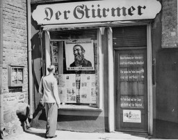 A young man looks at the antisemitic caricature in the display window of the Danzig office of "Der Stuermer." [LCID: 00240]