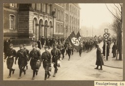 Uniformed members of the SA parade down a city street in Duisburg during a Nazi rally, circa 1928.