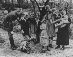 Nazi policy encouraged racially "acceptable" couples to have as many children as possible. Because of the number of children in this Nazi Party official's family, the mother earned the "Mother's Cross." Germany, date uncertain.