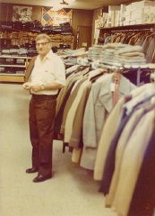 Aron standing in Howard's men's clothing store (named for his eldest son) at 9125 Commercial Avenue in Chicago. He opened the store in 1949 and owned it for 30 years. Chicago, Illinois, early 1970s.