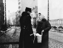 Policier polonais fouillant dans le sac d’un habitant juif du ghetto.