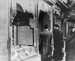 Shattered storefront of a Jewish-owned shop destroyed during Kristallnacht (the "Night of Broken Glass"). [LCID: 86838]