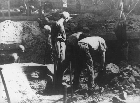 Prisoners at forced labor break stone with pickaxes in the quarry of the Flossenbürg concentration camp.