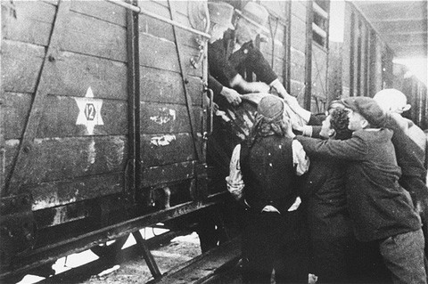 Jews load a barrel of water onto a deportation train in Skopje. [LCID: 79617]