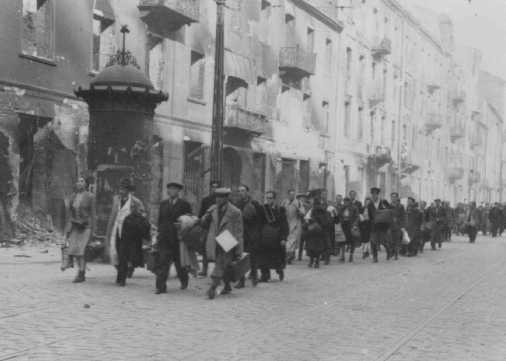 Jews rounded up during the Warsaw ghetto uprising are forced to march to the assembly point for deportation. [LCID: 34082]