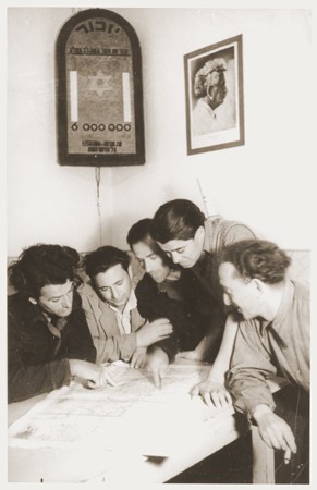 Members of Kibbutz Nili (a Zionist agricultural collective) study a map of Palestine. [LCID: 30035a]
