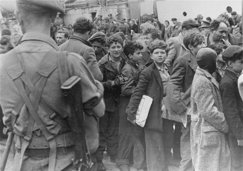 British soldiers transfer children refugees from the Aliyah Bet ("illegal" immigration) ship "Theodor Herzl" to a vessel for deportation to Cyprus detention camps. Haifa port, Palestine, April 24, 1947.