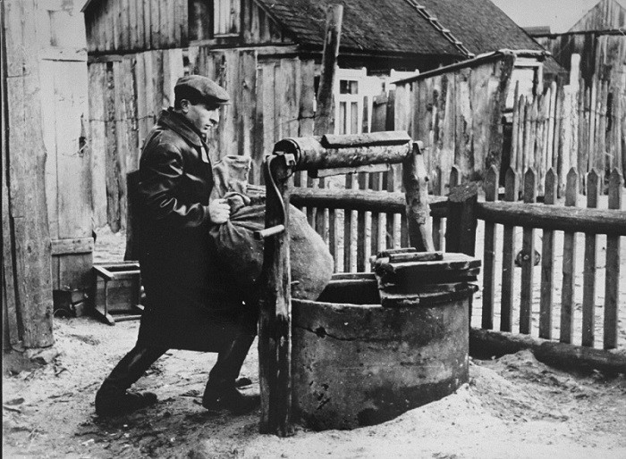 Photograph taken by George Kadish: a member of the Kovno ghetto underground hides supplies in a well used as the entrance to a hiding ... [LCID: 81109]