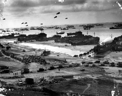 The Normandy beach as it appeared after D-Day. Landing craft on the beach unload troops and supplies transferred from transports offshore.