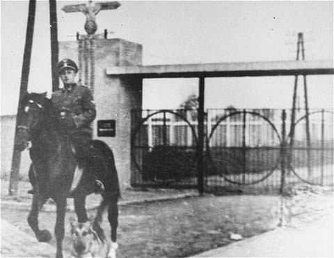 SS Second Lieutenant Gustav Willhaus, camp commandant, rides past the main gate of the Janowska concentration camp.
