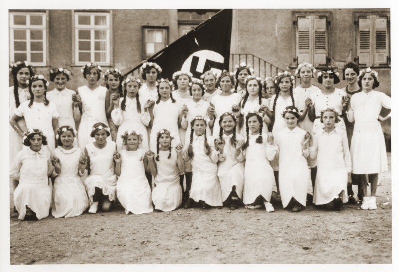Group portrait of German girls posing outside their school in front of a Nazi flag. [LCID: 97273]
