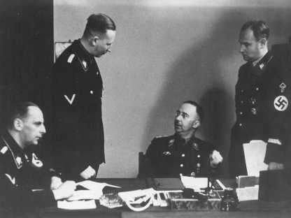 Heinrich Himmler (seated, center), chief of the SS, with Reinhard Heydrich (standing, left), chief of the Security Police and SD. Berlin, Germany, 1938.