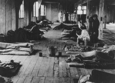 Women prisoners lie on thin mattresses on the floor of a barracks in the women's camp in the Theresienstadt ghetto. [LCID: 40228]