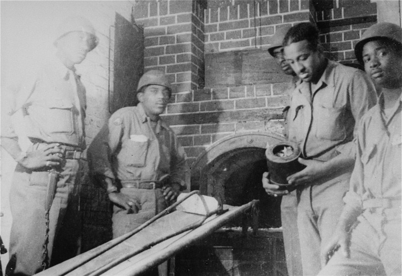 African American soldiers pose next to an oven in the crematorium of the Ebensee concentration camp.