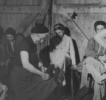 Soon after liberation, a British woman helps a camp survivor try on shoes. [LCID: 45014]