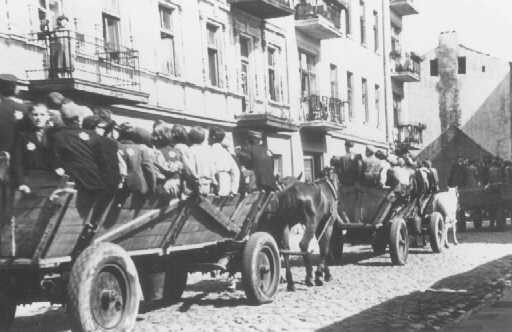 Jews, mostly children, proceed on horse-drawn wagons to assembly points for deportation.