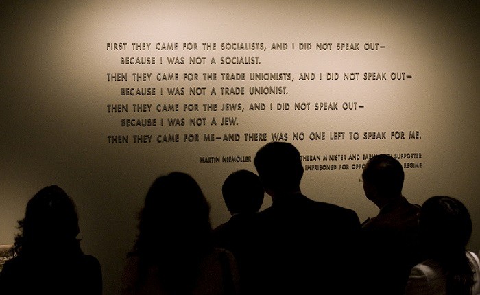 Visitors stand in front of the quotation from Martin Niemöller that is on display in the Permanent Exhibition of the United States Holocaust Memorial Museum.