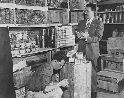 Morris Laub (right), Joint Distribution Committee director for Cyprus, reviews supplies sent for the 12,000 Jews still interned on the island.