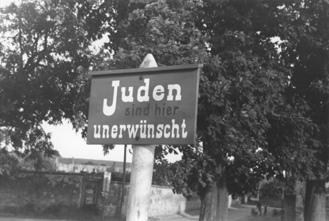 An anti-Jewish sign posted on a street in Bavaria reads "Jews are not wanted here." [LCID: 64416]
