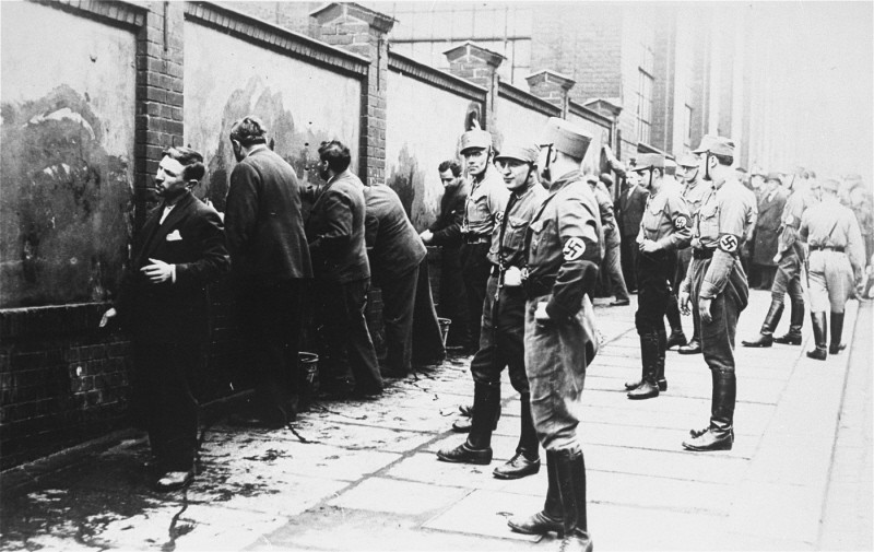 Political opponents of the Nazis, guarded by SA (Storm Troopers), are forced to scrub anti-Hitler slogans off a wall shortly after ... [LCID: 31368]