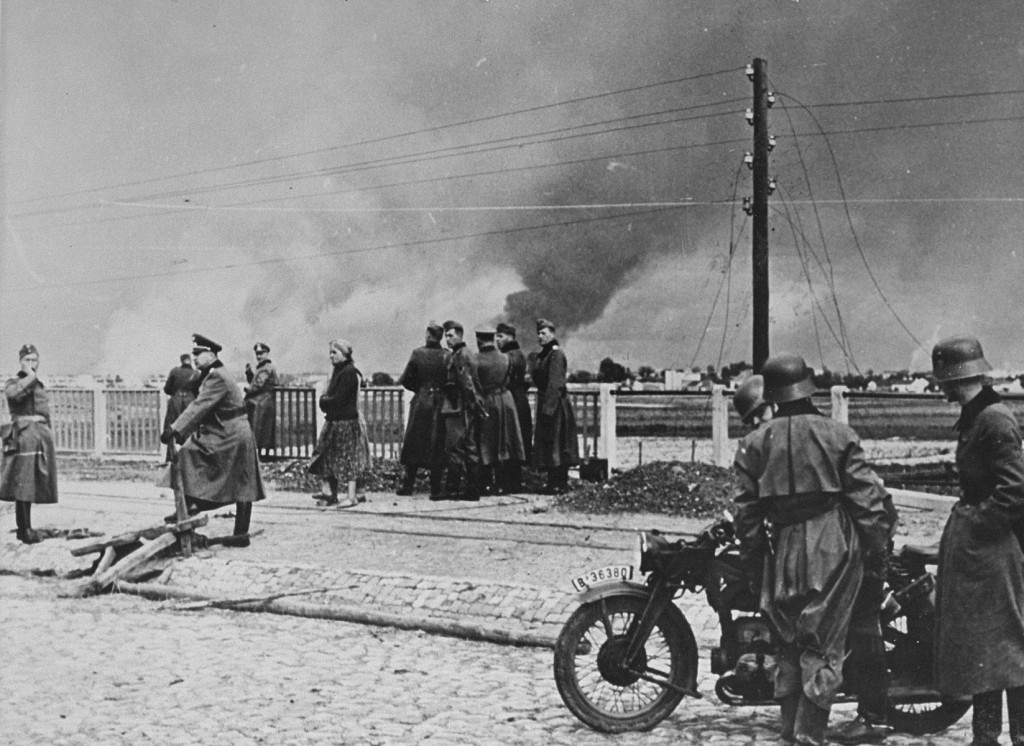 German forces in the outskirts of Warsaw. In the background of the photograph, the city burns as a result of the German military assault.