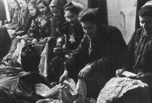 Jewish women who were seized for forced labor sort expropriated cloth. [LCID: 80417]