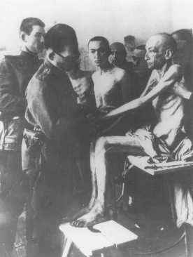 Soon after liberation, a Soviet physician examines Auschwitz camp survivors. [LCID: 45411b]