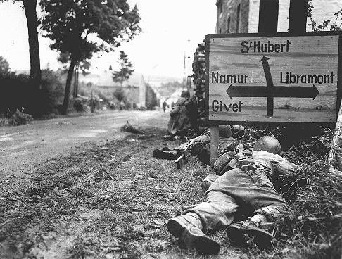 American soldiers of the 8th Infantry Regiment seek cover behind hedges and signs to return fire to German forces holding the town ... [LCID: 80482]