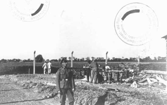 An SS guard watches prisoner laborers at construction work. [LCID: 83526]