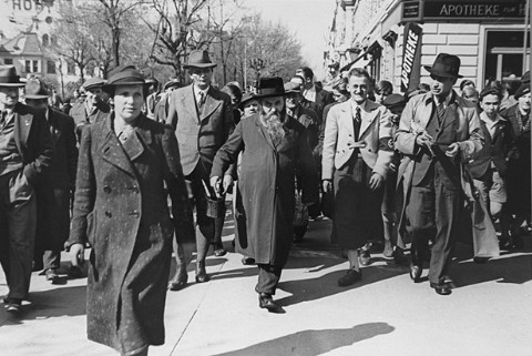 Two Jewish men (center, and at right in overcoat), carrying paint and brushes, who were forced by Austrian Nazis to paint "Jude" on the fronts of Jewish-owned businesses.