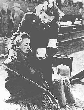 <p>A Red Cross official gives assistance to a former concentration camp prisoner who was transported to Sweden under an agreement with the Swedish Red Cross. Malmo, Sweden, April 1945. [Please contact Beth Hatefutsoth for copies of this photograph.]</p>