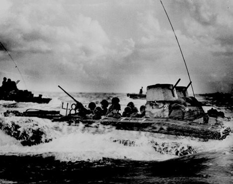 An amphibious troop carrier loaded with American Marines heads for the beaches of Tinian, an island in the Pacific Ocean.