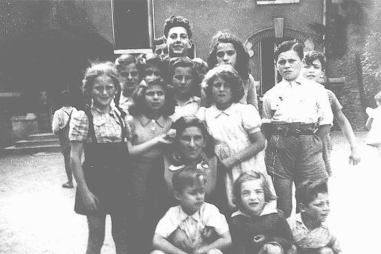 <p>A group of children surrounding Hermine Markovitz at the Children's Aid Society (Oeuvre de Secours anx Enfants; OSE) home for children in Draveil. France, postwar.</p>