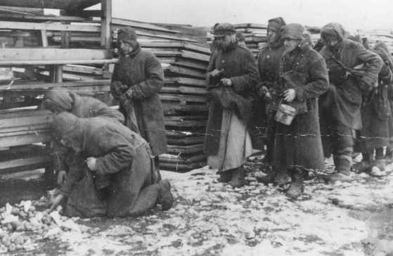 Soviet prisoners of war pause for rations during forced labor at the narrow-gauge railroad station.