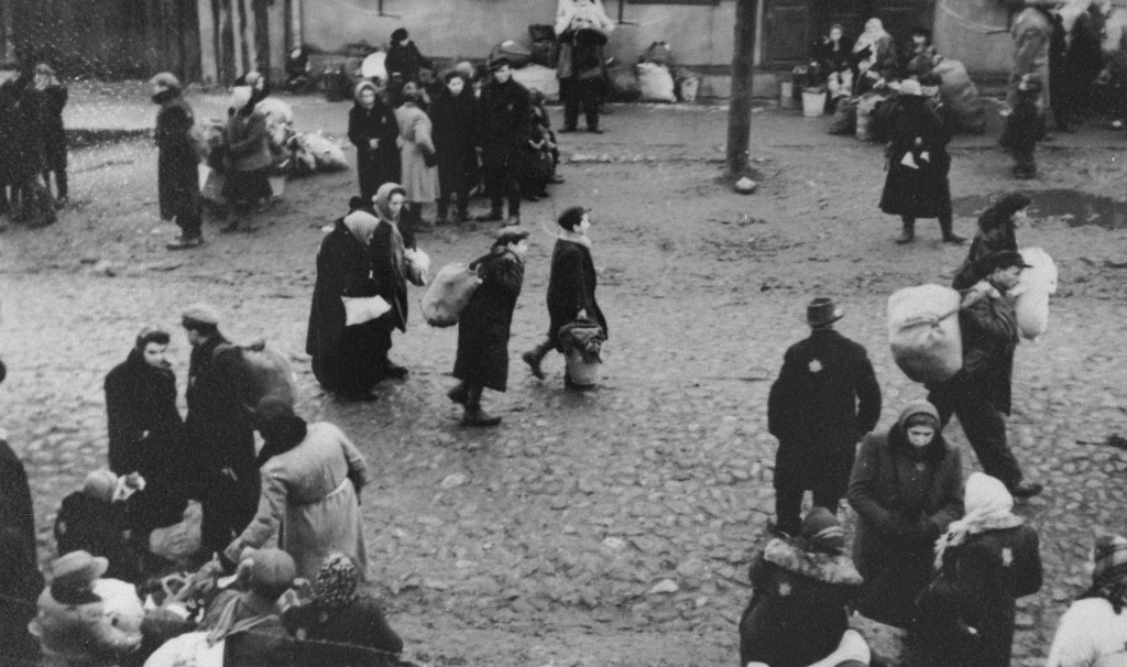 Jews carrying bundles of possessions who were forced to gather at an assembly point before their deportation from the Kovno ghetto, probably to Estonia. Kovno, Lithuania, October 1943.
This photograph was taken by George Kadish. 