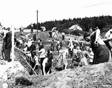 German civilians from the town of Nammering, under orders of American military authorities, dig graves for victims of a death march from the Buchenwald concentration camp. Germany, May 1945.