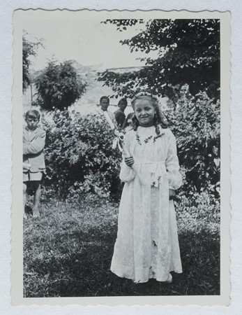 Selma Schwarzwald poses outside while wearing her first communion dress. [LCID: 58258]